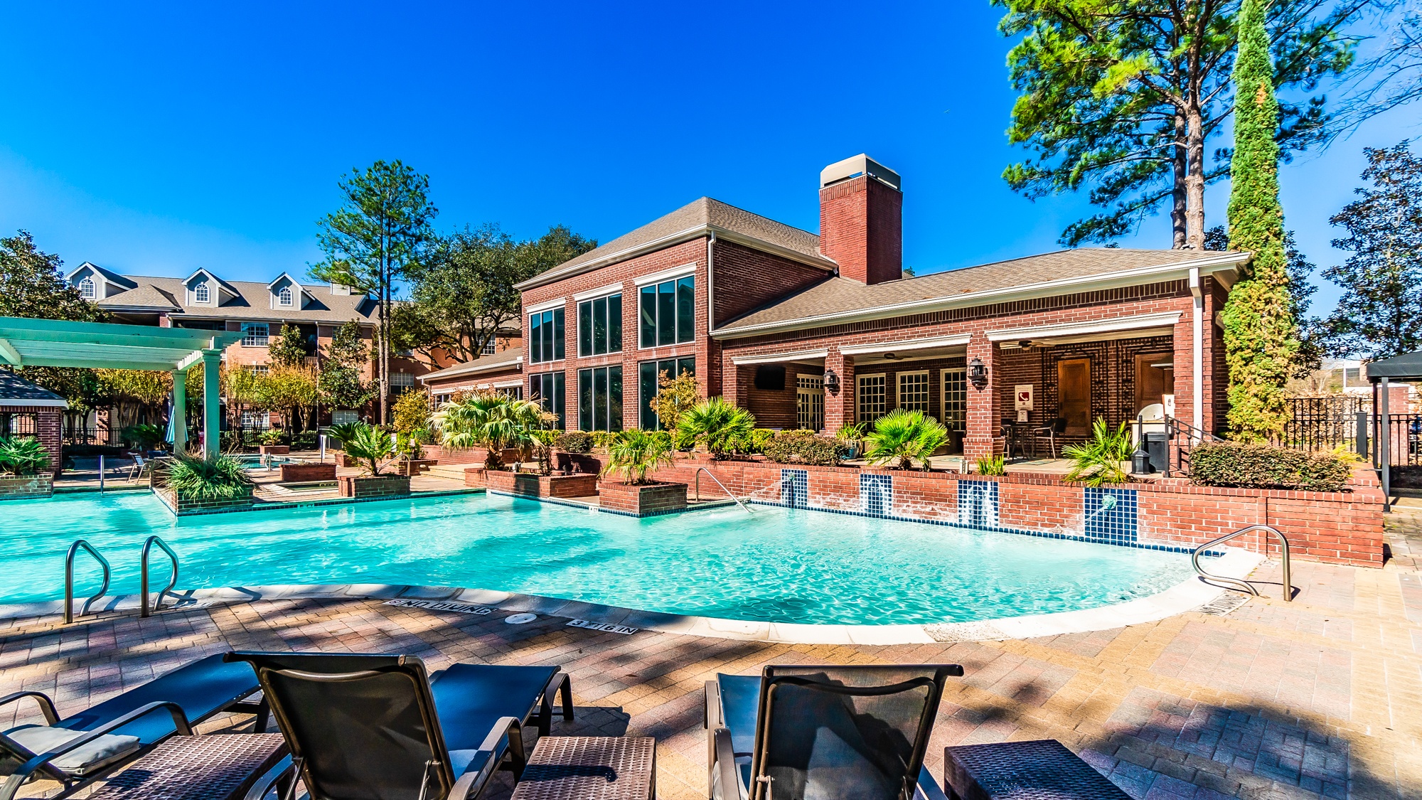 A pool with chairs and a building in the background.